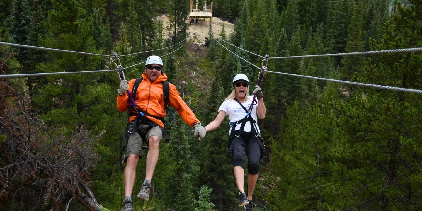 people holding hands on a mountain zip line ride