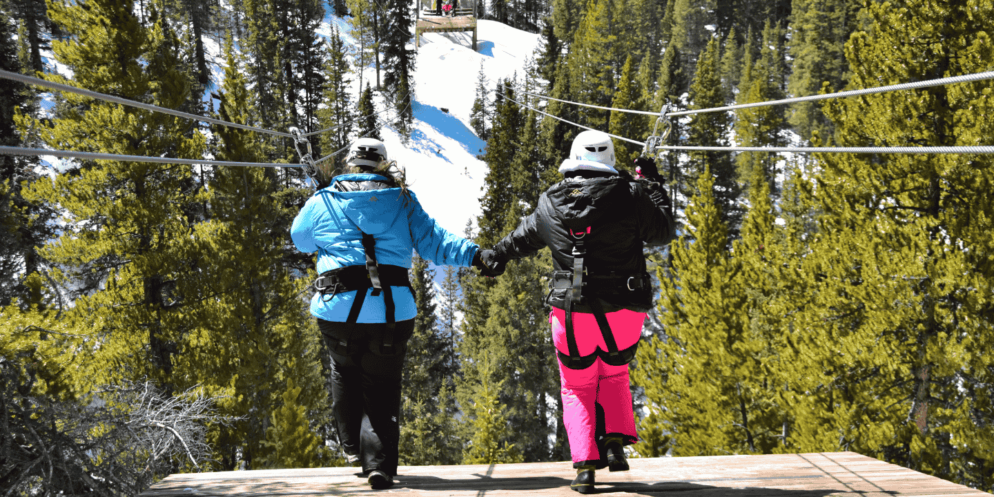 people zip lining in the trees and snow on a zip line and colorado snowmobile tour combo