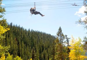 person zip lining above fall color trees in Leadville