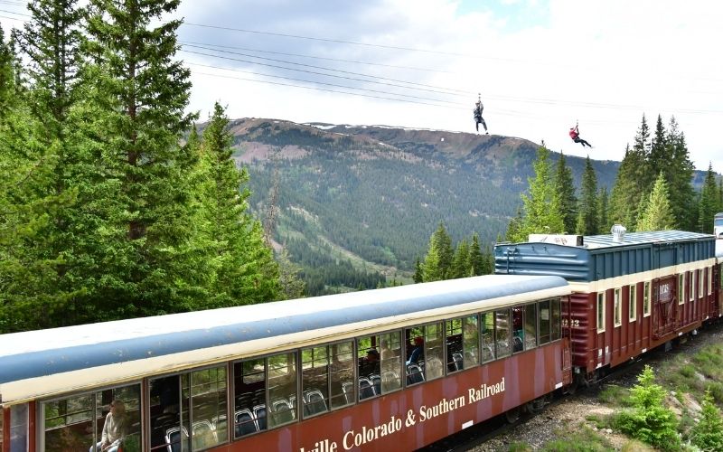 people zip lining over a moving train high in the Rockies in Leadville