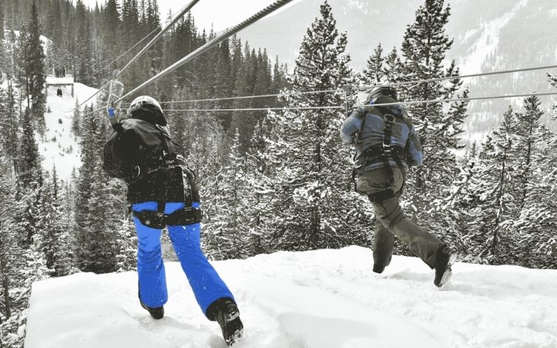 two people ziplining in the snow in Colorado